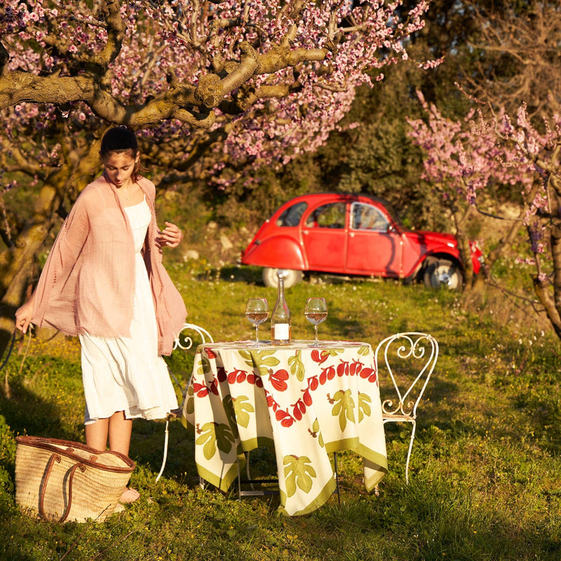 Couleur Nature - Fig Red & Green Tablecloth adorns a bistro table with wine glasses, embodying Southern France's charm in a springtime picnic setting.