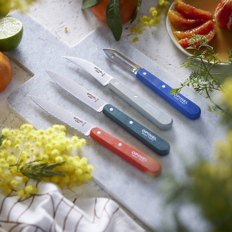 Opinel | Essential Small Kitchen Knife Sets Landscape: Five-piece knife set with colorful handles on a marble board, surrounded by citrus and herbs, showcasing craftsmanship and versatility.
