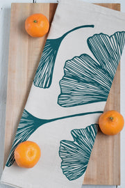 Hearth and Harrow Ginkgo Leaf Tea Towel in Green displayed with oranges, showcasing its organic cotton texture and eco-friendly design.