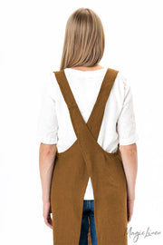 Woman wearing MagicLinen's pinafore cross-back linen apron with front pocket, ideal for cooking and gardening, highlighting its durable and stylish design.