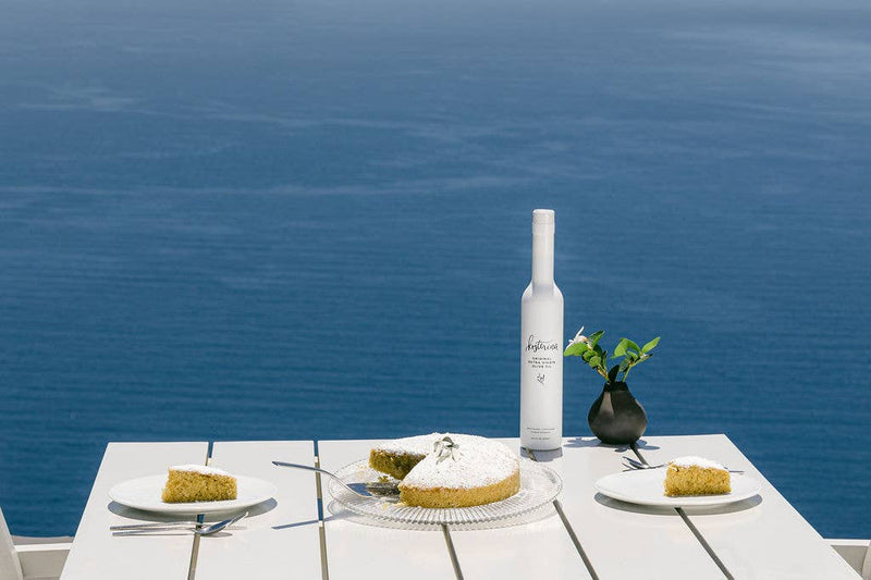 Kosterina - Original Extra Virgin Olive Oil (375ml) bottle on a table with plates of food and a wine bottle, highlighting its culinary use.