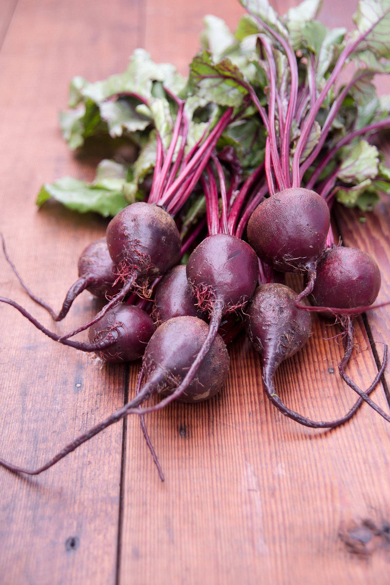 Bentley Seed Co. - Beets-Detroit Dark Red 1892: Fresh beetroots with leafy greens on wood, ideal for heart health and gardening.