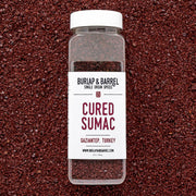 Burlap & Barrel - Cured Sumac (Sumak) - Single Origin Spice & Seasoning: 2.3 oz glass jar on deep-red spice bed, offering a bright, sour flavor.