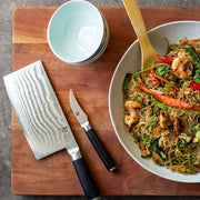 Shun | Classic Bird's Beak Paring Knife, 2.5 inches, with Damascus steel, rests beside a vibrant shrimp and vegetable glass-noodle stir-fry on a wooden board.