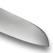 Close-up of the Shun Classic Santoku Ebony, 5.5 inches, showcasing its Damascus steel wavy pattern and finely honed edge, ideal for precise kitchen tasks.