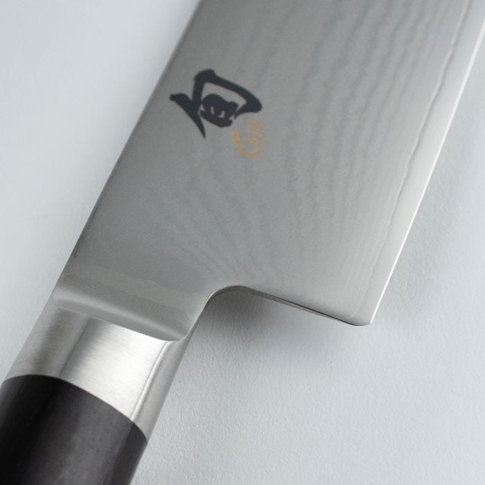 Shun Classic Nakiri Ebony, 6.5-inch knife with polished stainless-steel blade and kanji mark, transitioning into a dark wood handle, perfect for vegetable preparation.