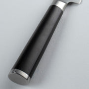 Close-up of the Shun Classic Serrated Utility Knife's handle, featuring a smooth black grip with metal accents, ideal for precise kitchen tasks.