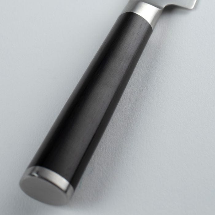 Close-up of the Shun Classic Serrated Utility Knife's handle, featuring a smooth black grip with metal accents, ideal for precise kitchen tasks.