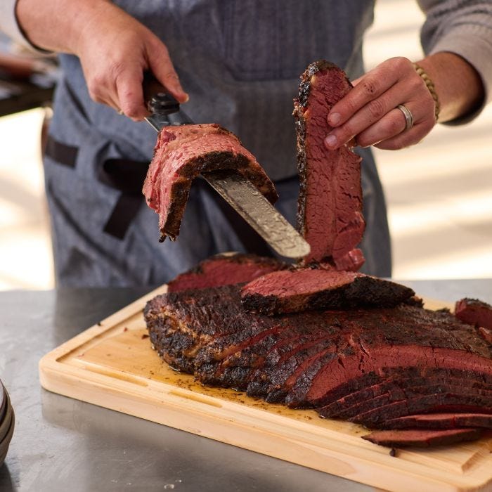 Shun Classic Hollow Ground Brisket Knife effortlessly slicing smoked brisket, showcasing its precision for perfect, juicy cuts, ideal for Athens Cooks' culinary expertise.