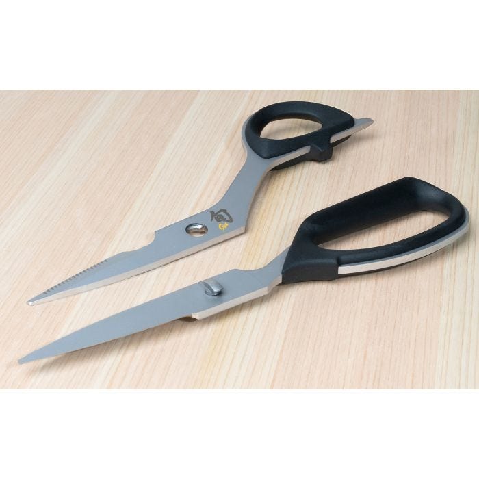 Shun Kitchen Shears, 9 inches, with metal blades and black-plastic handles, separated on a light wood surface, ideal for versatile kitchen tasks and easy cleaning.