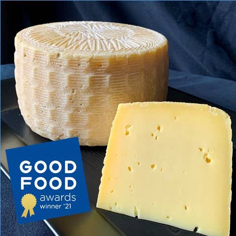 Tulip Tree Creamery - Milkweed: 5 oz. Wedge, a washed rind, Alpine-style cheese with a sweet, nutty flavor, shown with a cheese wheel and slice.