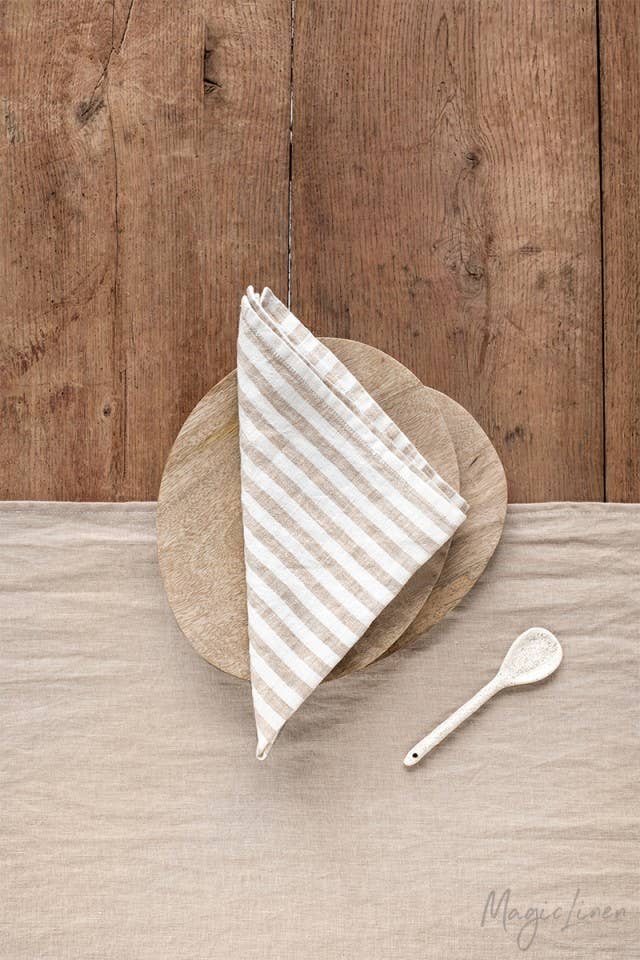 Set of 2 linen napkins displayed on a wooden plate with a spoon, highlighting premium quality and versatility for stylish table decor from Athens Cooks.