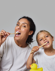 Woman and girl brushing teeth using Davids kids + adults nano-hydroxyapatite premium toothpaste, promotes natural whitening and enamel health, 4 oz, mild mint flavor.