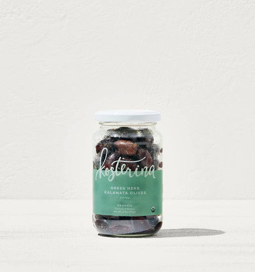 Kosterina - Greek Herb Kalamata Olives in a jar on a white surface, perfect for salads or snacking, featured at Athens Cooks.