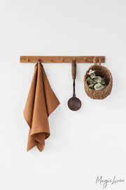 Linen tea towel hanging beside a potted plant, showcasing its absorbent and durable fabric, ideal for kitchen tasks.