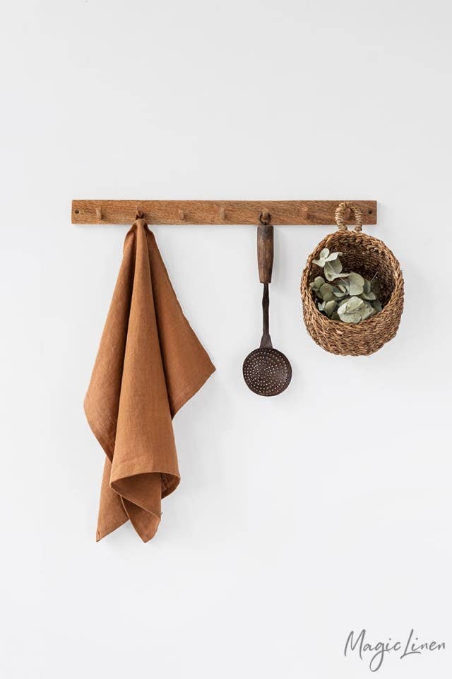 Linen tea towel hanging beside a potted plant, showcasing its absorbent and durable fabric, ideal for kitchen tasks.