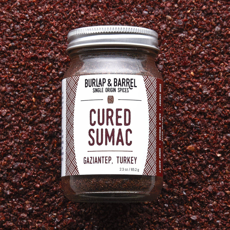 Burlap & Barrel - Cured Sumac, 2.3 oz jar, on coarse granules; a Middle Eastern spice with bright, sour flavors, ideal for enhancing various dishes.