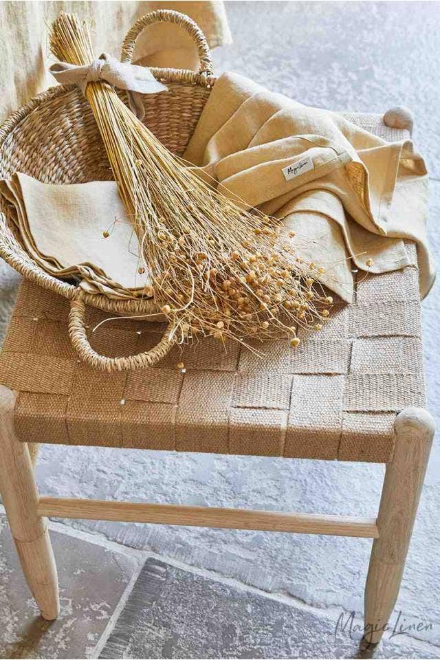Wicker basket holding MagicLinen - Linen Tea Towels on a chair, showcasing durable, absorbent linen kitchen towels ideal for maintaining a tidy kitchen.