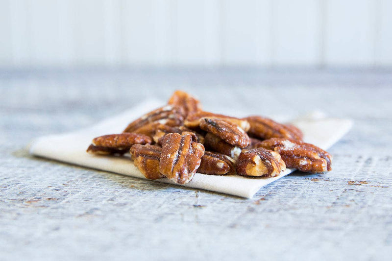Schermer Pecans - GLAZED PECANS - Georgia Pecans, shown as a pile of roasted pecan halves on a white napkin, perfect for gifting or culinary uses.