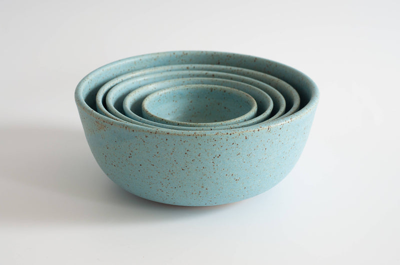 RachaelPots - Nesting Bowls Set Of Five: Light Blue, speckled stoneware bowls stacked neatly, showcasing hand-trimmed foot and varying sizes for versatile kitchen use.