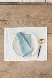 Set of 2 linen napkins on a wooden table with a spoon and placemat, embodying MagicLinen's sustainable, timeless table décor style.