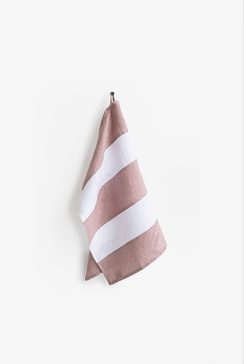 Striped linen tea towel hanging on a hook, featuring a loop for easy storage. Part of MagicLinen's zero-waste program, made from soft, absorbent European flax.