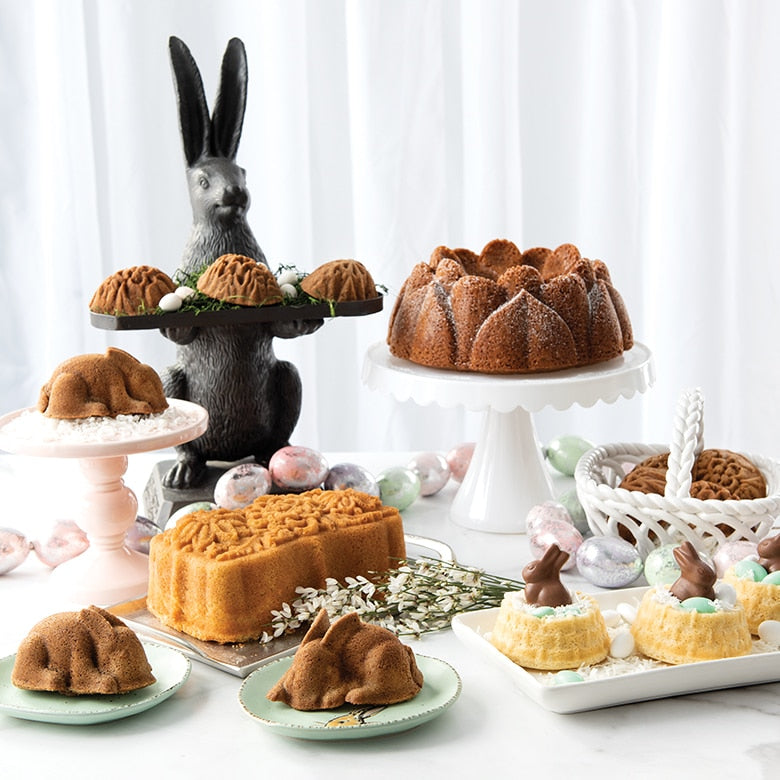 Nordic Ware | Baby Bunny Cake Pan amid cakes and bunny-themed decor, showcasing its detailed design and generous capacity for baking adorable bunny-shaped cakes.