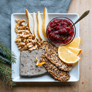 Beth's Farm Kitchen - Cranberry Sauce - Low Sugar! on a snack board with pâté, walnuts, pears, crispbreads, orange slices, and evergreen garnish.