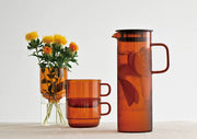 HARIO USA - HARIO Colors Glass Cold Brew Pitcher, 800ml: Amber, featuring a slender design with a black lid and strainer, perfect for infusing and serving cold beverages.