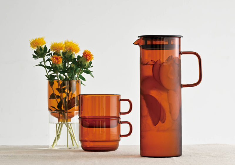 HARIO USA - HARIO Colors Glass Cold Brew Pitcher, 800ml: Amber, featuring a slender design with a black lid and strainer, perfect for infusing and serving cold beverages.