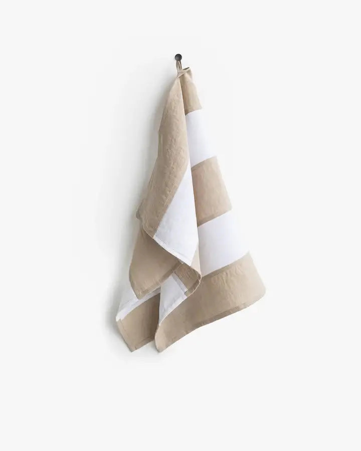 Striped linen tea towel with hanging loop on a hook, part of a zero-waste program by MagicLinen, ideal for stylish and functional kitchen use.