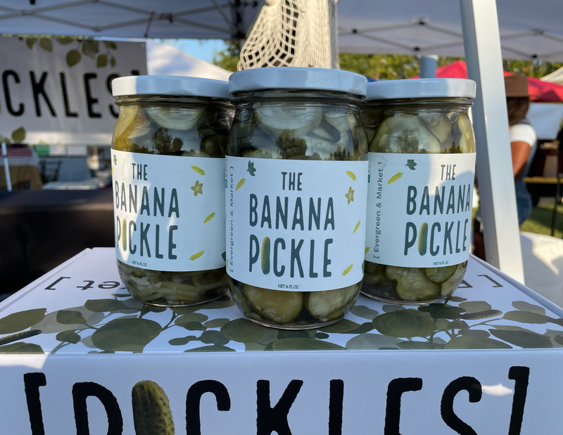 PICKLES by Evergreen and Market - The Banana Pickle jars displayed at a market stall, showcasing sweet, spicy, and sour pickled banana slices in brine.