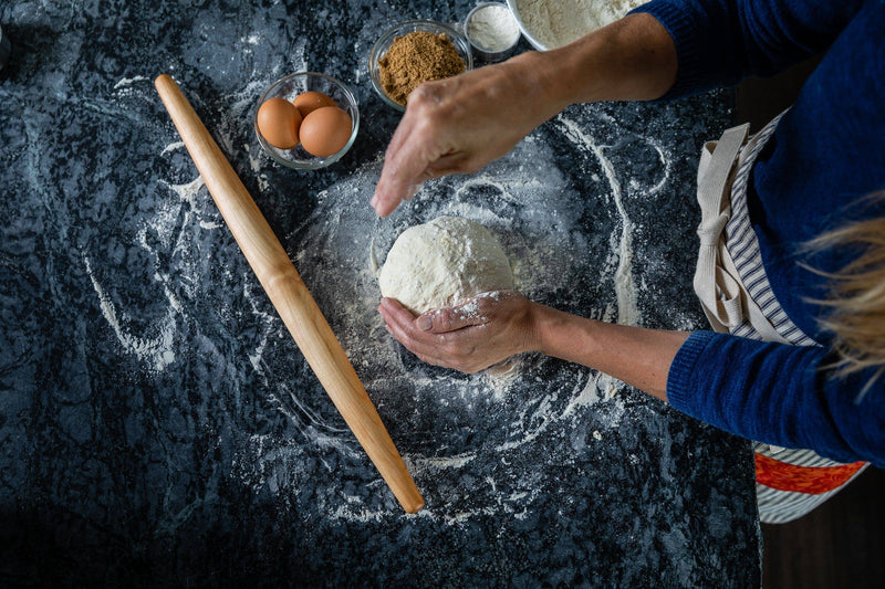 Person using the Earlywood | French Rolling Pin - Jatoba, showcasing its contoured silhouette and tapered design for precise dough rolling.
