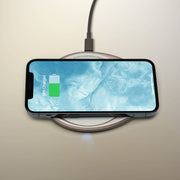 OHOM - Ui 3 Self-heating Mug Set's charging pad wirelessly charges a smartphone, illustrating its dual functionality on a neutral surface.