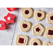 HIC - Harold Import Co. - King Arthur Thumbprint Cookie Cutters 4-Piece Set creating embossed dough with jam centers, featuring heart, star, circle, and square shapes on a baking sheet.