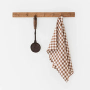 Brown and white checkered linen tea towel on a rack, showcasing its absorbent and durable European fabric ideal for kitchen tasks.