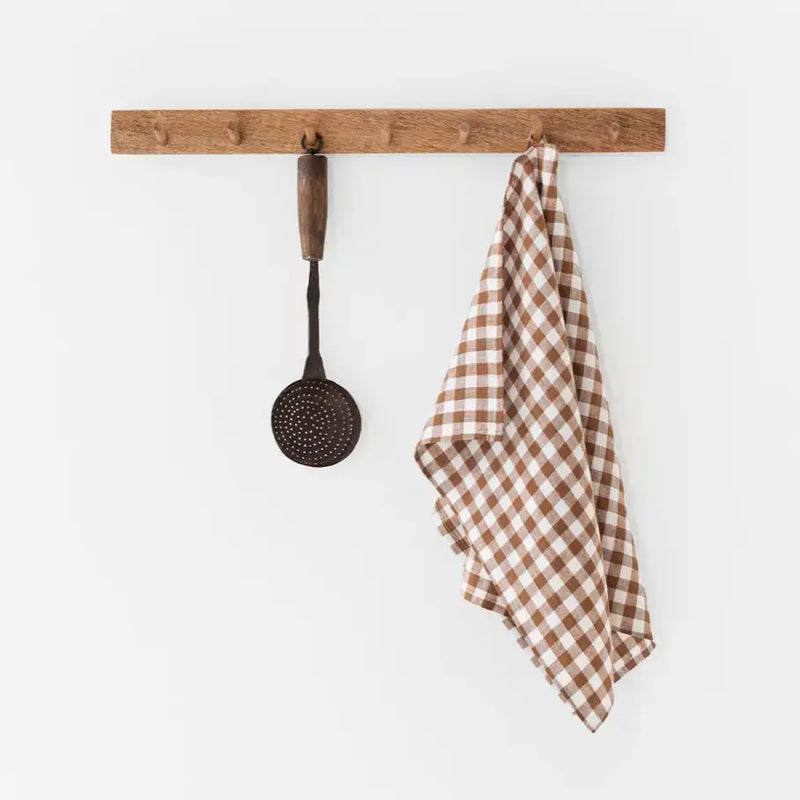 Brown and white checkered linen tea towel on a rack, showcasing its absorbent and durable European fabric ideal for kitchen tasks.