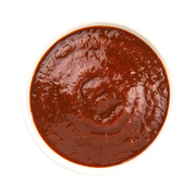 Beth's Farm Kitchen BBQ Sauce in a small white bowl, showcasing its thick, red texture. Ideal for enhancing dishes with its apple-infused smoky flavor.