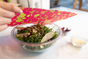 Bee's Wrap - Assorted 3 Pack - Splendid Spring: A person holds Bee's Wrap over a salad, showcasing reusable food storage wraps in action.