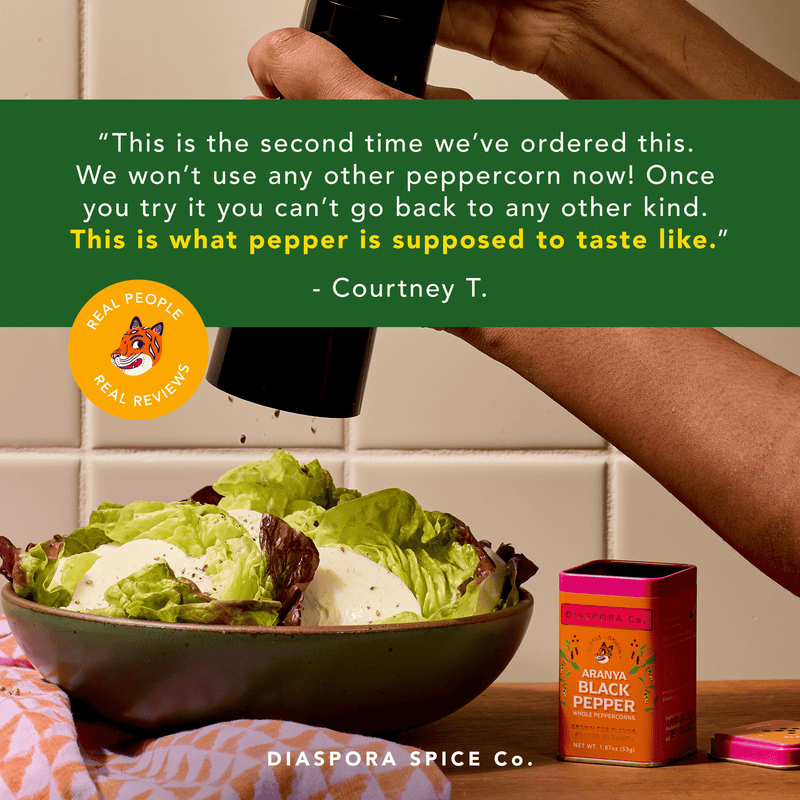 Diaspora Spices Co. - Aranya Black Pepper (Whole), 53g tin, with customer praise, displayed beside salad; highlights single-origin, vine-ripened flavor from family-run farm.