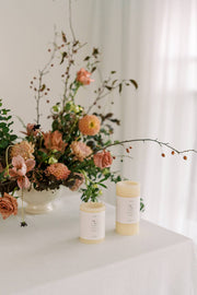 Mo&Co Home - 100% Beeswax Pillar Candles in a natural white finish, displayed alongside a floral arrangement and vase, ideal for home decor and celebrations.