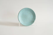 RachaelPots - Dessert Plate: Sage, a hand-thrown, speckled turquoise ceramic plate with a subtle upturned lip, displayed on a stand. Ideal for desserts.