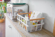 Yamazaki Home | Steel + Wood Storage Basket, Large, holds assorted breakfast items on a kitchen counter, showcasing its stylish organization for Athens Cooks' curated kitchen essentials.