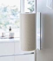 Yamazaki Home's Magnetic Steel Paper Towel Holder, White, mounted in a modern kitchen, showcasing its slim, space-saving design and magnetic attachment.