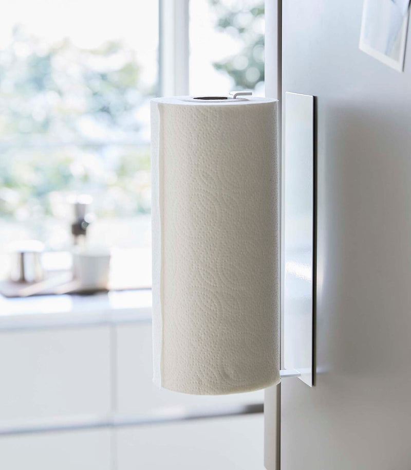Yamazaki Home's Magnetic Steel Paper Towel Holder, White, mounted in a modern kitchen, showcasing its slim, space-saving design and magnetic attachment.