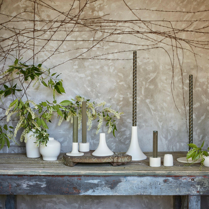 The Floral Society candle holders in varied shapes with a matte finish, designed to fit standard taper candles, showcasing the Grand Tall Earth model.