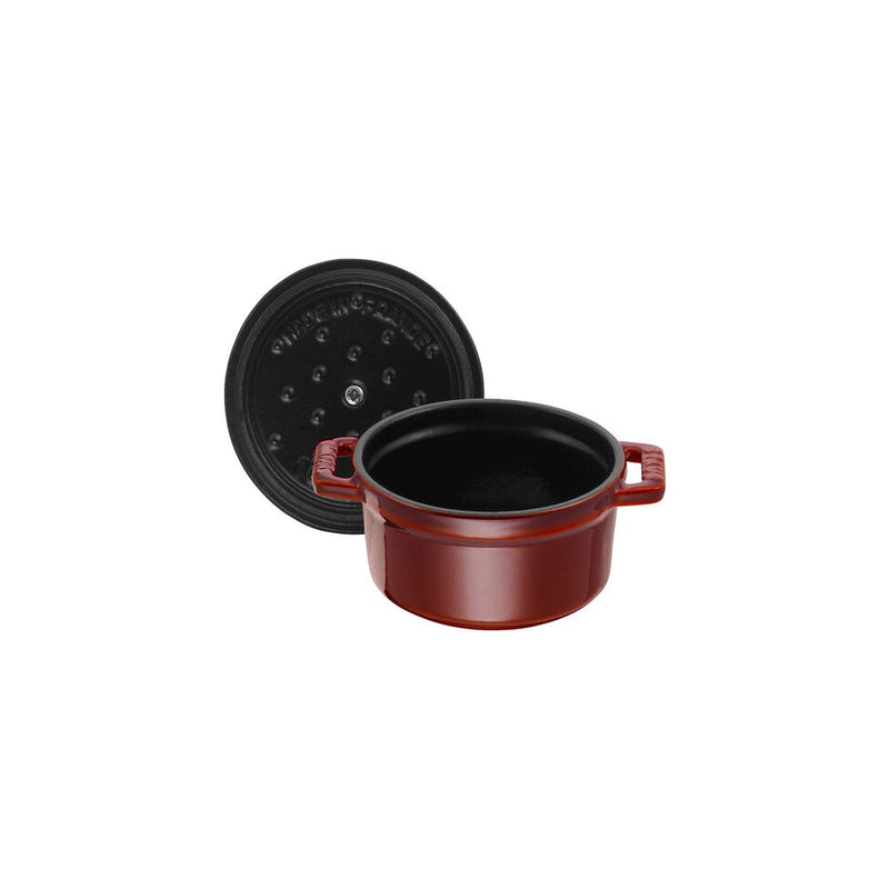 Staub Mini Round Dutch Oven, Grenadine, 0.25 QT., features a red enameled cast-iron pot with a black interior and matching lid, perfect for single-serve cooking.