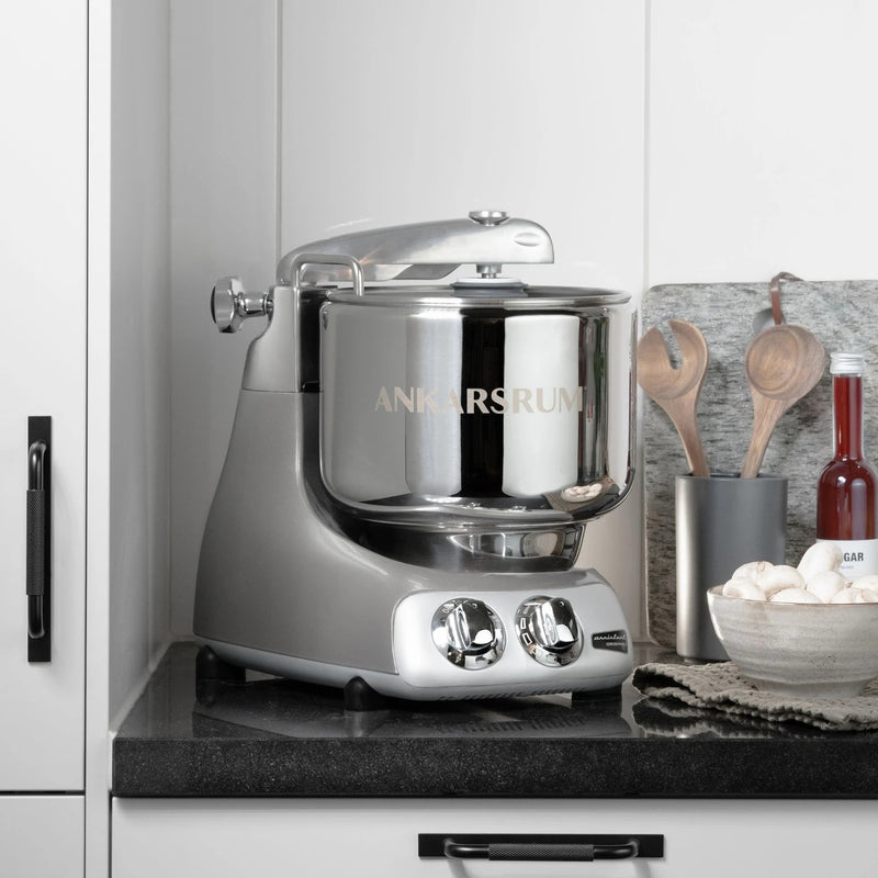 Ankarsrum stand mixer on countertop with wooden spoons and mushrooms, reflecting quality kitchen tools from Athens Cooks.