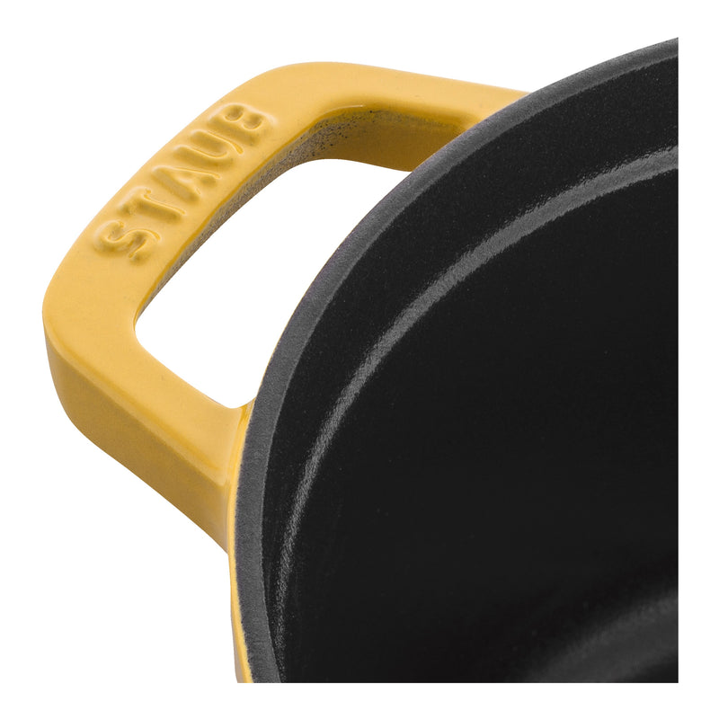 Staub Mini Round Dutch Oven, Citron, 0.275 QT., showcasing its yellow enamel handle with “STAUB” cast into it, and the black interior.