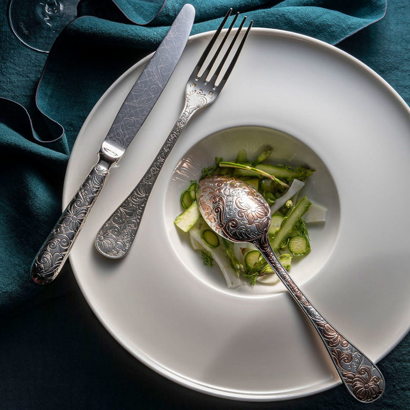 Christofle | 5-Piece Place Setting Jardin d'Eden Silver Plated with engraved floral utensils on a bowl of sliced vegetables, showcasing elegant, nature-inspired dining.